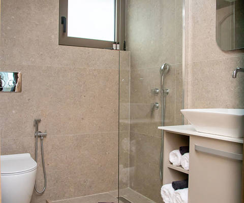 Modern bathroom with walk-in glass shower, wall-mounted toilet and vanity with towels