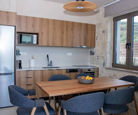 Modern kitchen with wooden cabinets, dining table, large window, and stainless steel appliances
