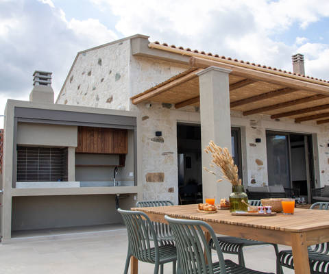 Outdoor dining area with breakfast setup, barbecue station and view of a beautiful stone villa